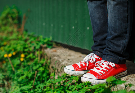 红运动鞋穿混凝土在灌木之间视图片