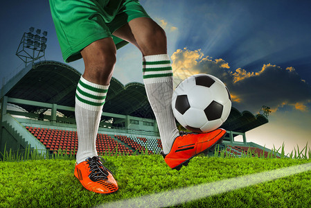 足球运动员在足球运动场上的腿脚踝上拿着足球图片