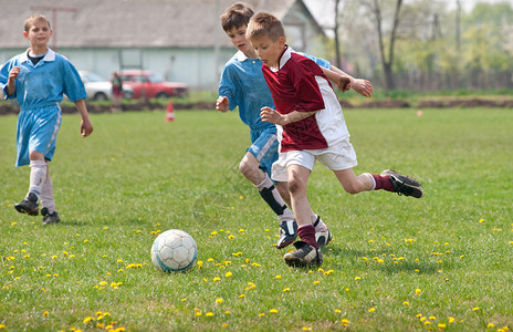 在运动场上踢足球的小男孩图片