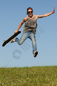 敏捷休闲的年轻男滑板手在他的滑板上高跃起图片