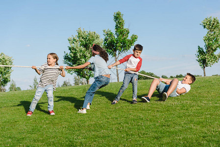 多民族儿童拉绳子在公园背景图片