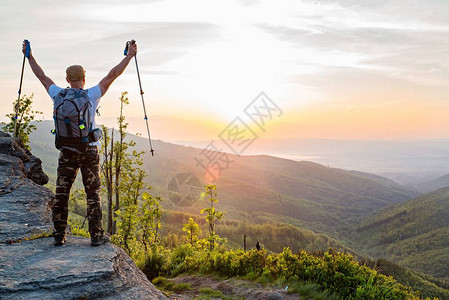 日出时山顶有高杆登山旅游的男子图片