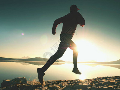 活跃的运动员赛跑者在日出岸上奔跑的剪影早晨在沙滩上进行健康生活方式锻炼男子图片