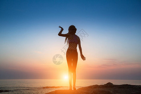 剪影灵活的女孩在暮色中在海边跳舞图片