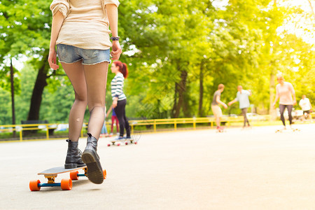 身穿黑靴子和丝袜的少女在滑板公园户外玩长板游戏图片