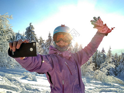 在雪山上穿滑雪衣的女孩子做自拍蓝色头盔图片