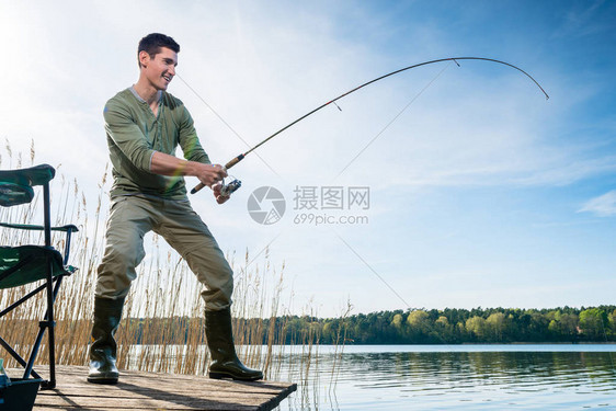 在蓝天下湖边钓鱼的渔夫蓝天图片