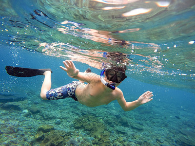 一个小男孩在印度尼西亚巴厘岛努沙佩尼达热带海域浮潜和背景图片