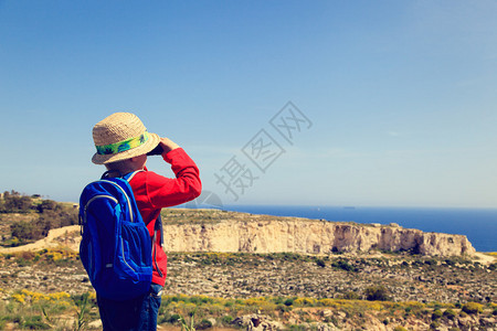 小男孩带着双筒望远镜在山上徒步图片