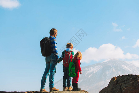 父亲和两个小孩在山上徒步旅行图片