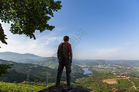穿着背包的人站在山顶上欣赏着葡萄牙杜罗谷的景色图片