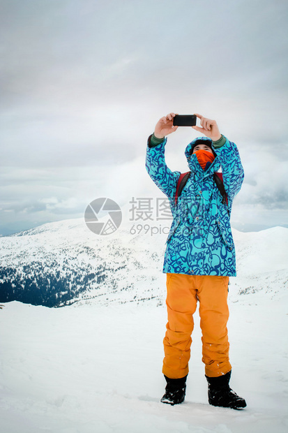 英俊的年轻人在山上用动作相机拍自在最美丽的地图片