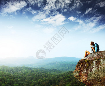 背着包坐在悬崖上仰望天背景图片