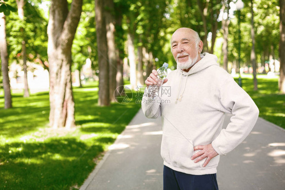 快乐的老年男跑步者正在休息在公园慢跑图片