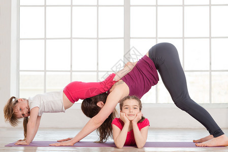 年轻母亲和女儿在家中做瑜伽练习背图片