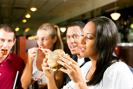 朋友一对是非裔美国人在快餐店里吃汉堡包和苏图片