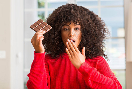 非裔美国妇女在家里吃巧克力棒时用手顶着嘴唇喝巧克力图片