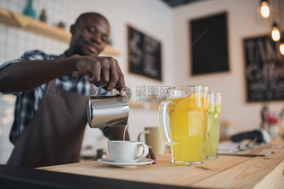 英俊的非洲裔美国咖啡师在咖啡馆的吧台上把牛图片