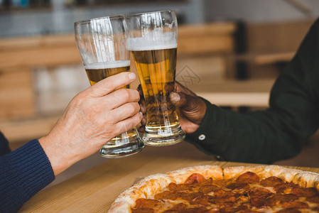 朋友在披萨店喝啤酒杯的图片