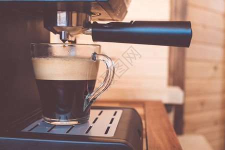 咖啡机在杯子里倒满了浓的新鲜咖啡图片
