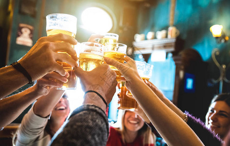 一群快乐的朋友在啤酒吧餐厅喝酒和敬酒与年轻人在凉爽的老式酒吧一起玩乐的友谊概念专注于中品脱玻璃高背景图片
