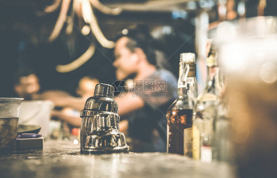 酒保和人们在鸡尾酒吧喝酒和玩乐的模糊散焦侧视图与人们一起享受时光的社交聚会概念以振动筛为重点的温暖图片
