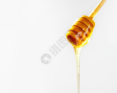 蜂蜜从木制花瓶上流下来在白色背景和复制图片