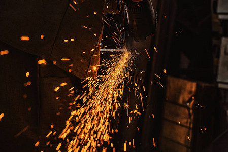 制造工人使用圆锯子在工厂中用火花显示的加工图片