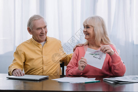 高龄夫妇坐在桌边拿着信封上面写着罗思伊拉图片