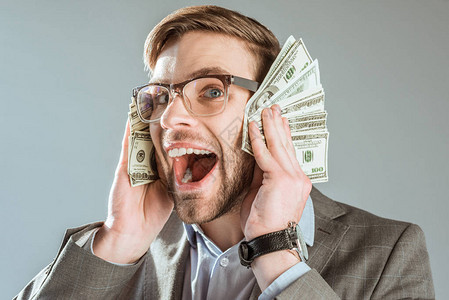 有钱快乐的生意人拿着美元钞票靠近他的脸部图片