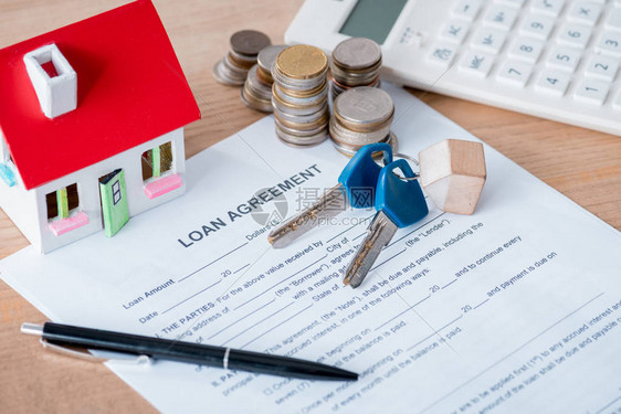 木板表面的贷款协议房屋模型钥匙图片
