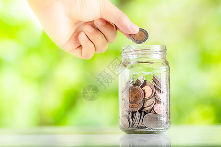 省钱利息植物生长在储蓄硬币中的钱在玻璃杯里用手放硬币省钱图片