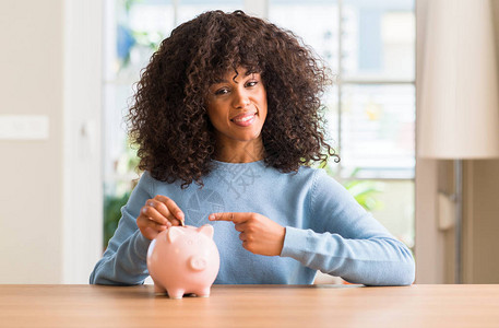 非裔美国女人在小猪银行存钱非常开心地用图片