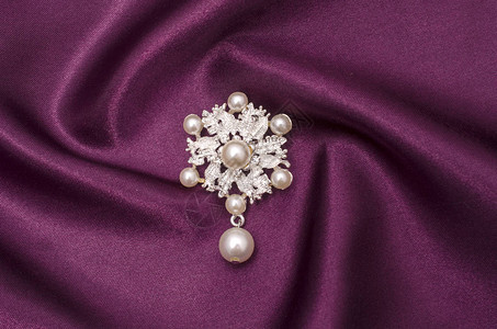 丝绸面料上饰有珍珠的胸针花图片