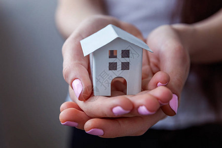 拿着小微型白色玩具房子的女手抵押财产保险梦想搬家图片