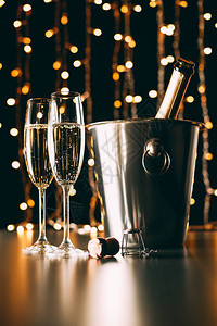 香槟瓶装在桶里杯子放在加兰轻光背景图片