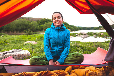 那个女孩坐在帐篷附近睡袋里的女人一个微笑的黑发在大自然中休息图片