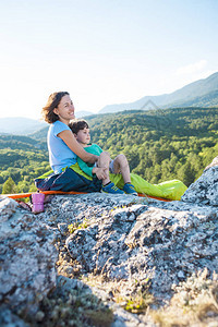 在山顶露营妈和孩子一起旅行一名妇女和她的儿子在攀登后休息睡袋里的女孩图片