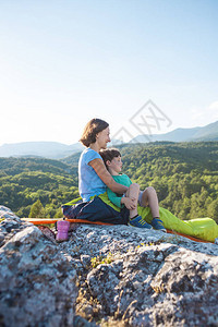 在山顶露营妈和孩子一起旅行一名妇女和她的儿子在攀登后休息睡袋里的女孩图片