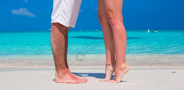 在白色沙滩上关闭男和女脚图片