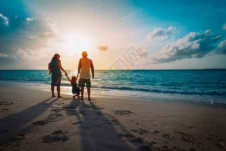 在日落海滩上快乐的家庭游戏在海上的妈图片