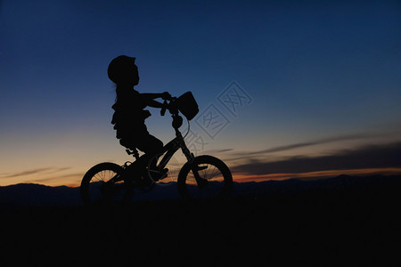 日落时骑自行车的小女孩图片