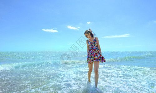 年轻微笑的女士在海浪中站立图片