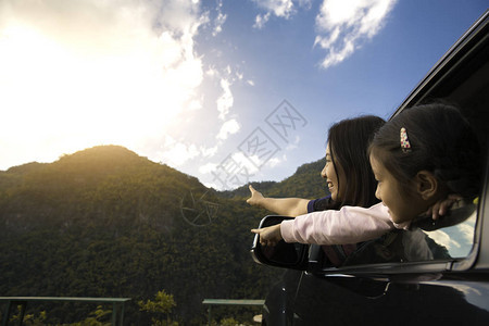 亚裔母亲和女儿可乘坐一辆具有山地背景的汽车旅行图片
