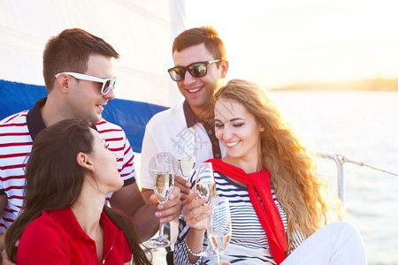 坐在游艇甲板上微笑的朋友和喝香槟的祝酒会图片