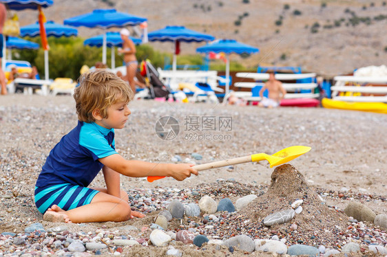 可爱的金发小男孩在海滩上建造鹅卵石城堡有趣的孩子在玩水桶和铲子假期图片