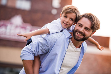 帅气的大胡子爸和他可爱的小儿子在外面玩耍时微笑着图片