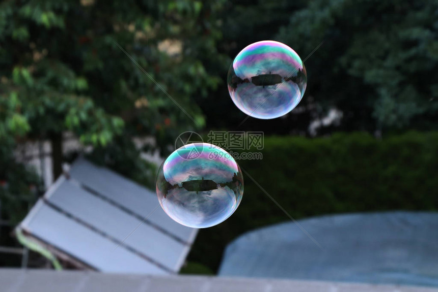 两个气泡在游泳池和花园上方的空中飞舞图片