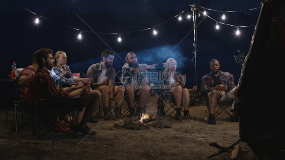 多民族的朋友在露营地的篝火旁放松图片