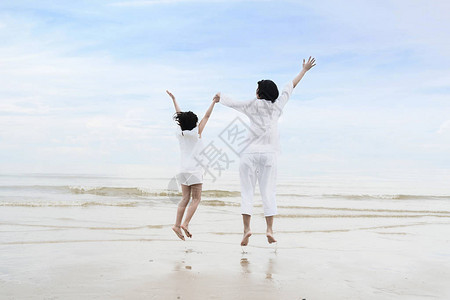 在暑假期间放松亚洲家庭时光有女儿拉着手玩乐和在海滩上跳图片